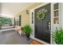 Inviting front porch featuring a swing, fern, bench, and a wreath-adorned front door at 1580 Lower Burris Rd, Canton, GA 30114