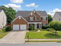 Charming two-story brick home with a manicured front yard, lush lawn, and two car garage at 3850 Calomel Dr, Cumming, GA 30040