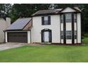 Inviting two-story home featuring solar panels, brown trim, a well-manicured lawn, and an attached garage at 3255 Hunters Crossing Pt, Lithonia, GA 30038