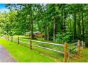 Serene home nestled among mature trees, featuring a grassy lawn with a charming wooden fence at 514 Macedonia Forest Circle Cir, Canton, GA 30115