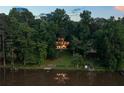 Scenic aerial view of lakefront property with a modern home surrounded by lush greenery at 132 Lakeshore Dr, Roswell, GA 30075