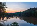Tranquil lake view at sunset showcasing the water reflecting the sky, with tree-lined shores at 132 Lakeshore Dr, Roswell, GA 30075