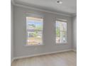 Bright living room with two large windows, light hardwood floors, and neutral paint at 271 Abbotts Crossing Cir, Conyers, GA 30094