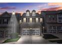 Charming brick townhome featuring a two-car garage at dusk under a colorful sky at 228 Stone Park Dr, Woodstock, GA 30188