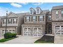 Inviting townhome featuring brick accents, two-car garage, and landscaped front yard at 228 Stone Park Dr, Woodstock, GA 30188