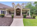 Inviting covered porch with stone columns, a brick base and walkway leading to the front door at 7269 Tyree Rd, Winston, GA 30187