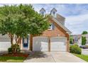 Charming townhome featuring a two-car garage, brick accents, and a well-manicured front yard with mature landscaping at 2421 Elkhorn Ter, Duluth, GA 30096