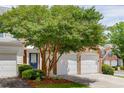 Brick townhome featuring a two-car garage, mature tree, and inviting blue front door at 2421 Elkhorn Ter, Duluth, GA 30096