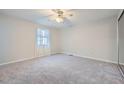 Spacious bedroom with plush carpet, a ceiling fan, and a large window for natural light at 6118 Dana Ct, Lithonia, GA 30058