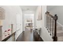 Bright foyer with dark wood floors, white trim, staircase, mirror console table, and decorative lighting at 7644 Rudder Cir, Fairburn, GA 30213