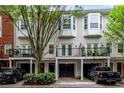 Three-story townhome featuring individual garages, wrought iron balconies, and a well-maintained brick paved driveway at 793 Inman Mews Ne Dr, Atlanta, GA 30307