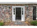 Close-up of a black front door with sidelights, framed by brick and adorned with elegant sconces at , Dunwoody, GA 30338