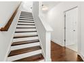 Elegant staircase featuring hardwood steps, white risers, and white walls leading to a bright entryway at 2140 Colvin Nw Ct, Atlanta, GA 30318