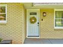 Close-up of the front door decorated with a seasonal wreath, framed by a brick facade and exterior lighting at 1848 Winthrop Se Dr, Atlanta, GA 30316