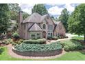 Elegant brick home with a lush front yard featuring tiered landscaping and mature trees at 1720 Monarch Ct, Cumming, GA 30041