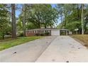 Charming single story brick home with mature trees, green grass, and a spacious driveway leading to a one-car garage at 3152 Ridgecrest Dr, Powder Springs, GA 30127