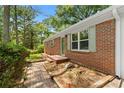 Charming brick home exterior featuring green trim, brick pavers, and a garden bed along the side of the house at 3152 Ridgecrest Dr, Powder Springs, GA 30127