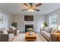 Cozy living room featuring a fireplace, plush seating, a ceiling fan, and bright, neutral decor at 6181 E Fayetteville Dr, Riverdale, GA 30296