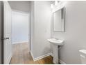 Modern half bath features a pedestal sink, wood-look floors, and neutral paint at 2058 Brookhill Way, Snellville, GA 30078