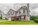 Split-level home shows two-car garage, neutral siding, brick accents, manicured lawn, and charming front entrance at 725 Signature Trce, Palmetto, GA 30268