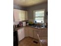 A functional kitchen with white cabinets, double sink, and window for natural light at 4513 College St, Forest Park, GA 30297
