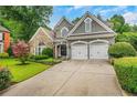 Two-story home featuring a stone facade, well-manicured lawn, and attached garage at 1473 Cardova Pointe, Dunwoody, GA 30338