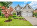 Beautiful gray home with a stone facade, a green lawn, and a two-car garage at 1473 Cardova Pointe, Dunwoody, GA 30338