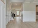 Bright entryway with light wood floors, white wainscoting, and view into living room with fireplace at 301 Moab Ct, Stockbridge, GA 30281