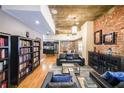 Open living room with a brick wall, hardwood floors, a bookshelf, and a leather sofa at 1026 Saint Charles Ne Ave # 15, Atlanta, GA 30306