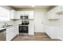 Bright kitchen featuring white cabinets, stainless steel appliances, and wood-look flooring at 6481 Alford Way, Lithonia, GA 30058