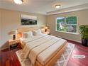 Comfortable bedroom featuring a large bed, tray ceiling, hardwood floors, and a bright window at 3695 Santa Rosa Way, Douglasville, GA 30135