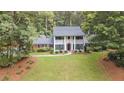 Expansive front lawn and mature trees frame this white two-story home with a brick accent and black shutters at 260 Waverly Hall Dr, Roswell, GA 30075