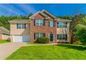Charming two-story home with a combination of brick and siding, a well-manicured lawn and an attached garage at 5018 Upper Elm St, Atlanta, GA 30349