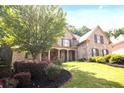 Charming brick home featuring a manicured lawn and a welcoming front porch with stone columns at 208 Grandmar, Canton, GA 30115