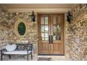 Elegant stone entryway showcasing double wooden doors with glass panels and a cute welcome mat and bench at 208 Grandmar, Canton, GA 30115