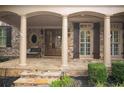 Inviting front porch with stone pillars, double doors, and a cozy bench, complemented by meticulously maintained landscaping at 208 Grandmar, Canton, GA 30115