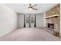 Inviting living room showcasing a stone fireplace, ceiling fan, and two windows for natural light at 3990 N Quail Dr, Douglasville, GA 30135
