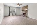 Spacious living room with a stone fireplace, a ceiling fan, and lots of natural light at 3990 N Quail Dr, Douglasville, GA 30135