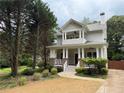 Charming two-story home featuring a welcoming front porch with brick and white pillars, manicured lawn and driveway at 2552 White Oak Dr, Decatur, GA 30032