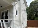 Side view of the home's exterior showcasing neutral siding, white trim, and a glimpse of the charming front porch at 2552 White Oak Dr, Decatur, GA 30032