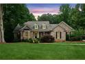 Charming brick home with manicured lawn and lush landscaping under a beautiful sunset at 3445 Strawberry Ln, Cumming, GA 30041