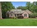 Beautiful brick home featuring a well-maintained lawn, mature trees, and manicured shrubs at 3445 Strawberry Ln, Cumming, GA 30041