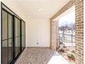 Covered patio featuring brick floor, black-framed sliding doors, and exterior access at 354 Olmstead Way # 27, Alpharetta, GA 30022