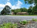 Low-angle view of a brick ranch home with a well-maintained lawn and mature trees at 1502 Campground Rd, Mcdonough, GA 30252