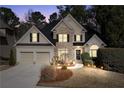 Charming two-story home featuring stone accents and a well-manicured front lawn at dusk with landscape lighting at 994 Fairview Club Cir, Dacula, GA 30019