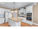 Bright kitchen featuring granite countertops, white cabinets, stainless steel appliances, and hardwood floors at 994 Fairview Club Cir, Dacula, GA 30019