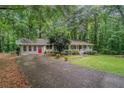 A single story home's long driveway leads to a classic exterior with a covered porch amidst a lush, wooded landscape at 5317 Highway 81, Loganville, GA 30052