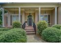 Inviting front porch featuring classic columns, a brick walkway, and lush landscaping leading to a stylish front door at 1065 Chippewa Oak Dr, Dacula, GA 30019