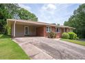 Single-story brick home with a carport, showcasing mature landscaping and an expansive driveway at 3332 Clay Rd, Austell, GA 30106