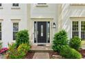 Home featuring a front door with glass panels, manicured bushes, and colorful garden area at 1667 Willow Way, Woodstock, GA 30188